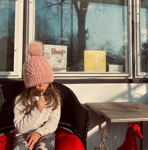 Adorable child in front of storefront window containing books, POOP: a book about going big potty and wonderful you are by deyani deydreaming